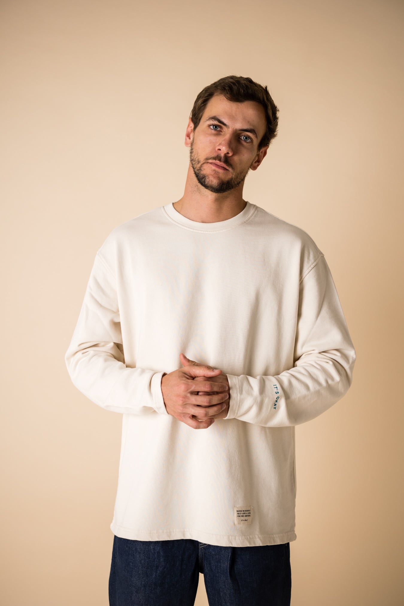 Blond man wearing an organic crew neck sweater in off-white, seamless design. Relaxed and minimal style, perfect for any occasion. Studio Photography gender neutral apparel