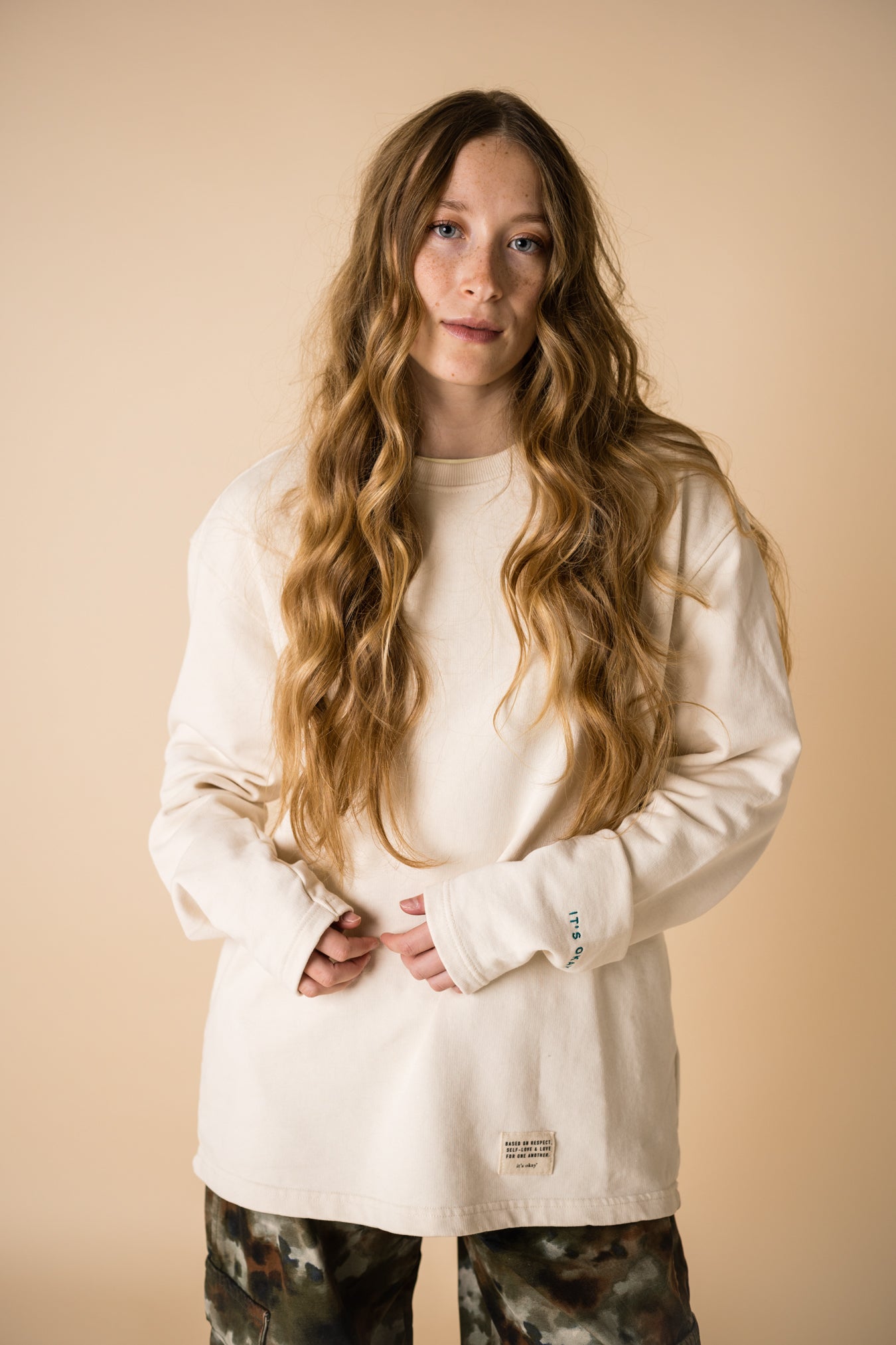 blond girl with blue eyes wearing an organic crew neck sweater in off-white, seamless design. Relaxed and minimal style, perfect for any occasion. Studio Photography gender neutral apparel